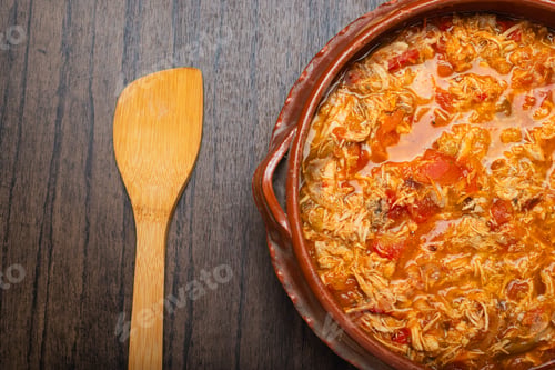 Preview: Authentic mexican chicken tinga, typical mexican food prepared in a clay pot on a wooden table.