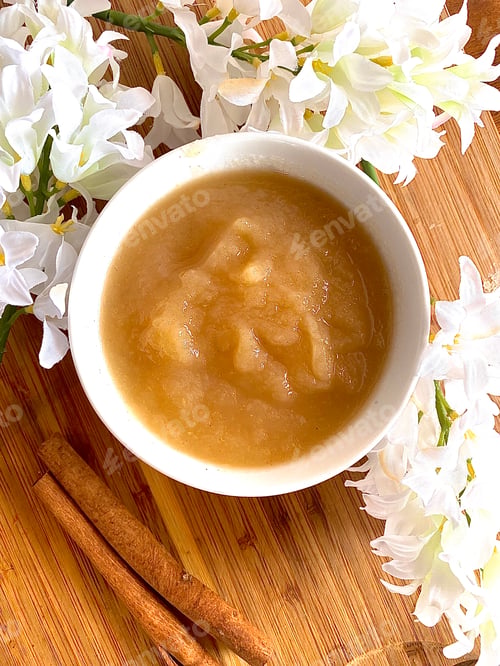 Preview: Applesauce in a bowl on wooden plate with flowers