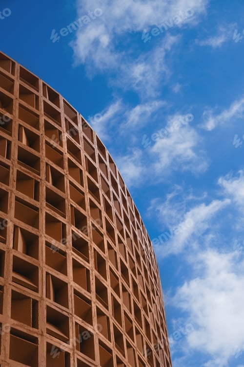 Preview: Closeup of geometric structure of peach fuzz colored concrete beam fragments against a blue sky