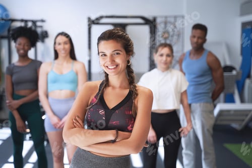 Preview: Confident sporty woman standing in front of a group of people at the gym.