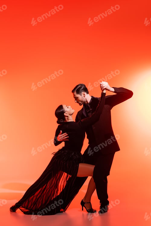Preview: Side view of professional dancers performing tango on red background