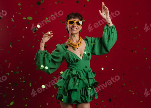 Preview: Happy young short hair woman in elegant dress gesturing while confetti flying against red background
