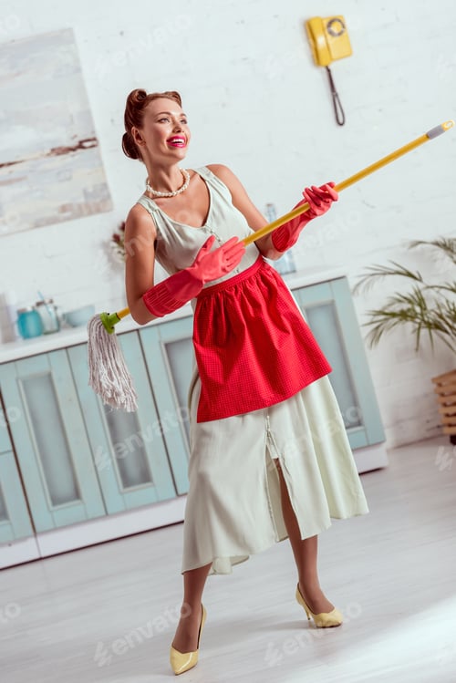 Preview: Pretty pin up girl in red apron and red rubber gloves dancing with yellow mop