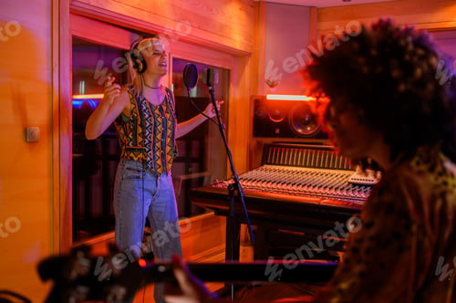 Preview: Portrait of a blonde singer woman recording a song on a microphone in a studio