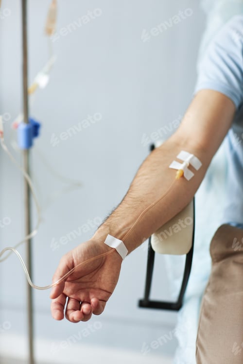 Preview: Closeup of male hand with IV drip infusion in treatment session at clinic