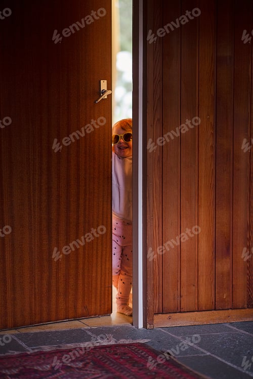 Preview: Young cheerful kid with sunglasses opening the door of a house