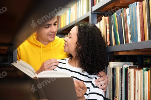 Preview: Students studying together near shelves with books in public library