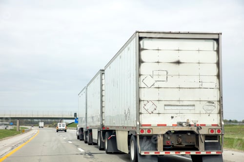 Preview: Three trailer road train transporting commercial cargo in USA highway. White vehicle rear cloudy sky