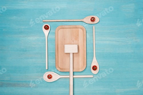 Preview: Top view of wooden cutting board, meat hammer and spoons with cherry tomatoes on table
