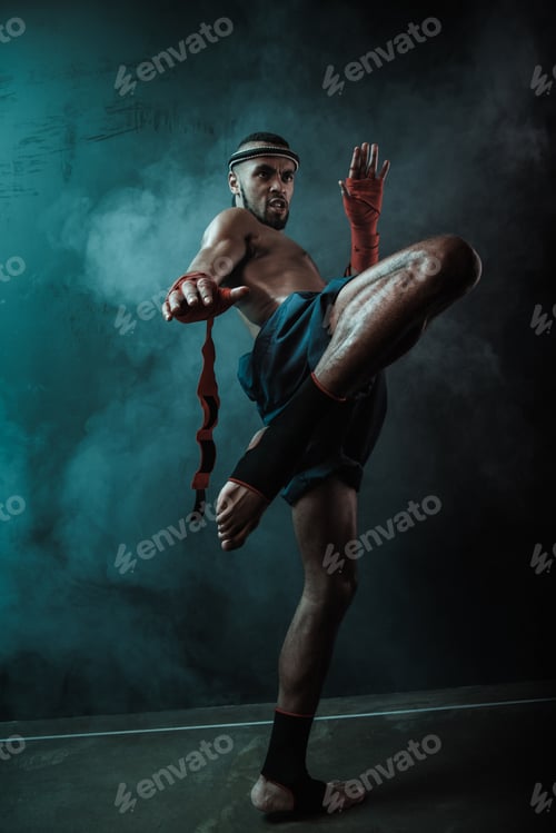 Preview: Low angle view of determined Muay thai fighter training thai boxing, ultimate fight concept