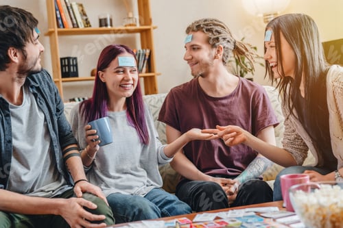 Preview: Smiling friends playing game guess who and having fun at home