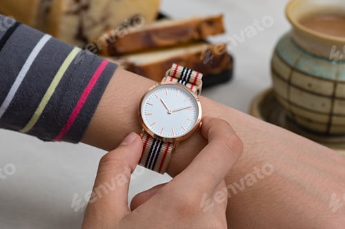 Preview: Hand on Wristwatch Beside Bread and Tea