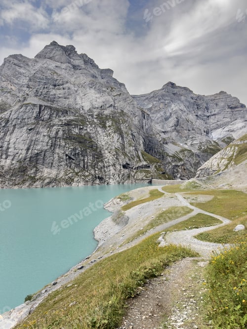 Preview: Mountain trail winding along turquoise alpine reservoir