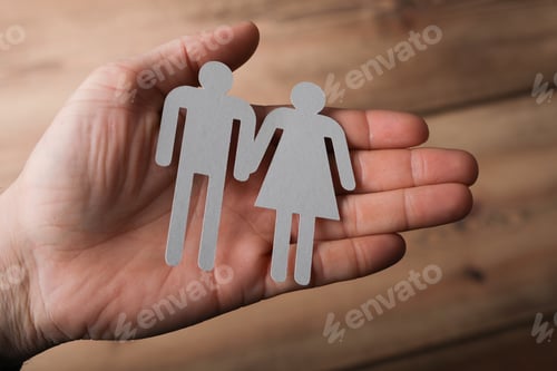 Preview: Closeup shot of a man holding grey female and male signs on a wooden background