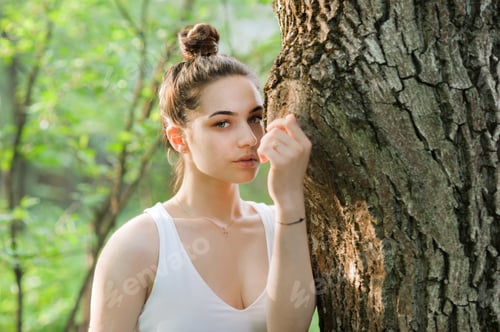 Preview: Woman Leaning on Tree Trunk in a Forest