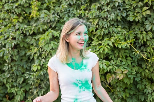 Preview: Holiday, holi and people concept - Beautiful young woman posing with green powder on her shirt