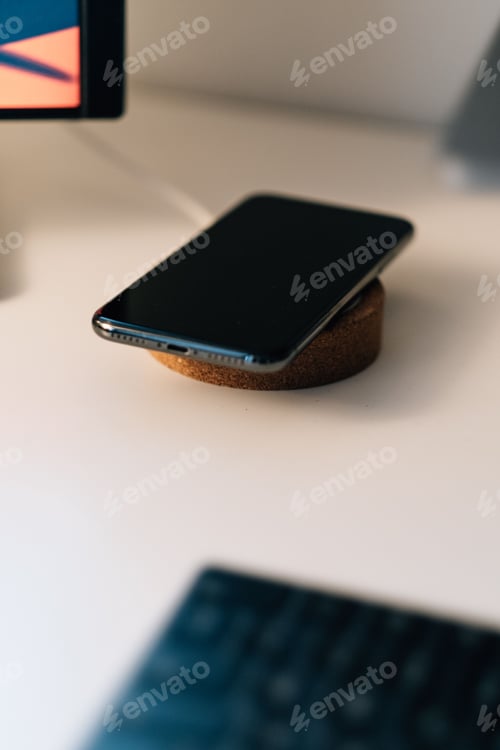 Preview: Shallow focus shot of a black mobile wireless charging on the table with electrical gadgets