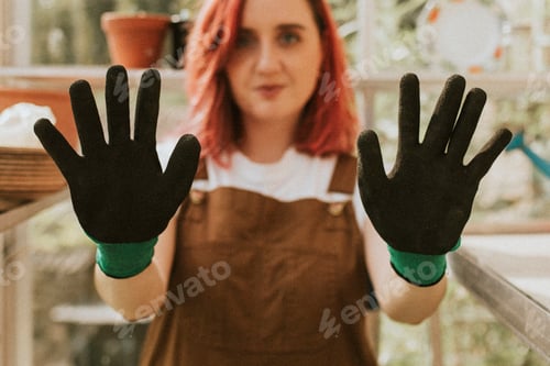 Preview: Young woman gardener with black gloves in small organic farm