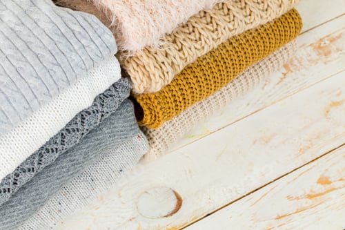 Preview: Stack of Folded Sweaters on Wooden Table