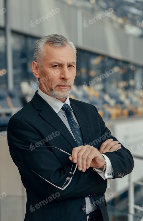 Preview: Serious businessman with arms crossed looking at camera