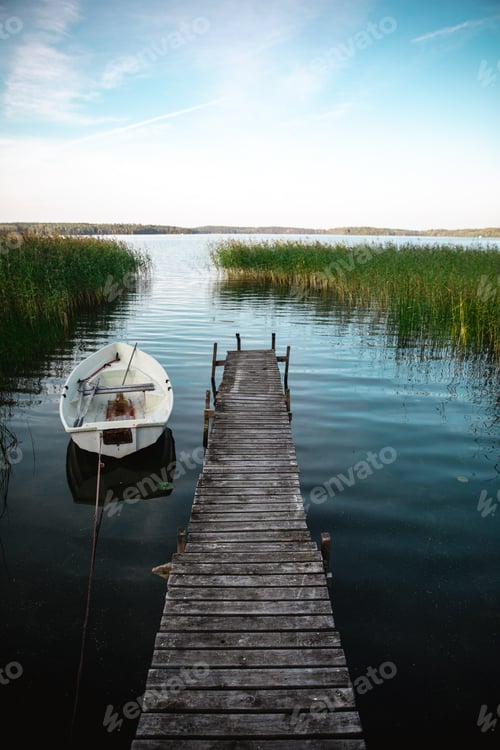 Preview: Vertical shot of a wooden pier and a boat on a calm lake during daylight