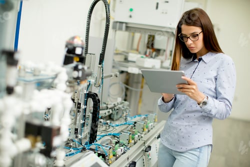 Preview: Young female student of robotics stands in a lab