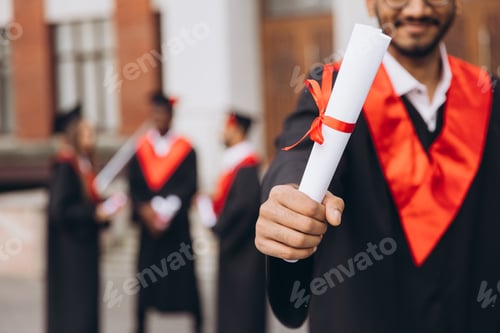 Preview: Young Graduate Holding Diploma During Outdoor University Graduation Ceremony