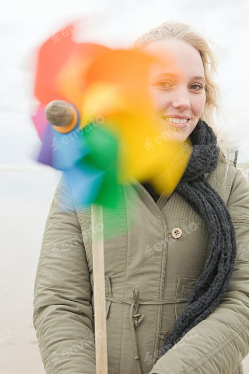 Preview: Smiling woman with a colorful pinwheel on a breezy day