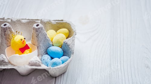 Preview: A small chicken in a paper egg tray next to a pile of yellow and blue eggs. Easter in Ukraine