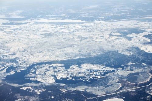 Preview: Aerial view from airplane window over clouds top to snow covered rivers, fields and roads