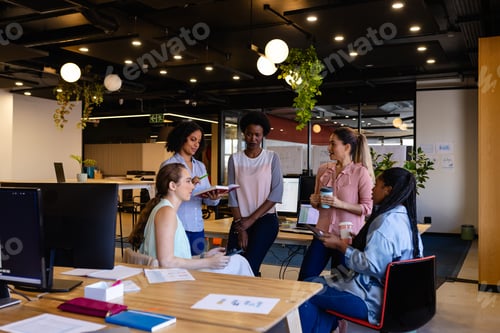 Preview: Diverse female colleagues in discussion using tablet in casual office meeting