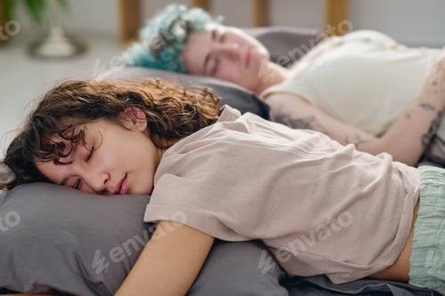 Preview: Young tired brunette woman in cotton t-shirt lying on soft grey pillow