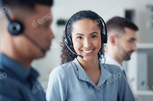 Preview: Portrait of a young call centre agent working in an office alongside her colleagues