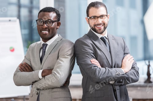 Preview: close up view of two multiethnic businessmen with arms crossed in office
