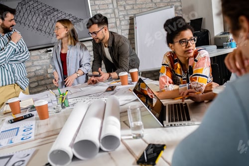 Preview: Group of modern business people in casual wear discussing architectural designs.