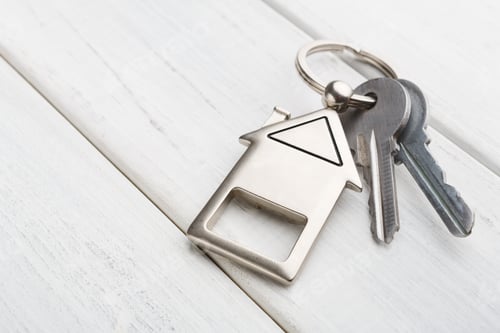 Preview: Bunch of keys with house shaped keychain on white wood
