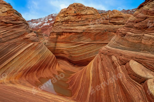 Preview: Stunning view of The Wave rock formation with vibrant sandstone layers and a clear blue sky.