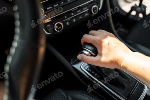 Preview: Driver hand rests on gear shift of automatic transmission in car