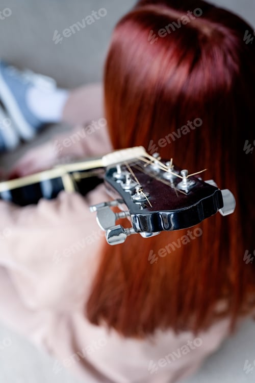 Preview: Young woman playing guitar at home