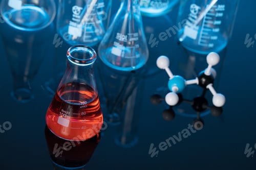 Preview: Glass flask with red liquid and a molecule structure on a lab table
