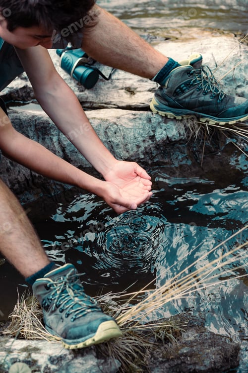 Preview: Man taking pure water from river and he is holding it in hands. Summer vacation trip close to nature