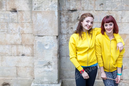Preview: Young women smiling, stone wall in background