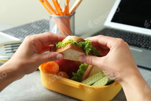 Preview: Workplace eating with female hands hold sandwich, close up