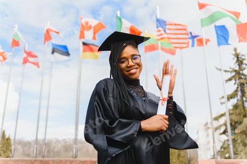 Preview: pretty african college student in graduation cap and gown in front of school building