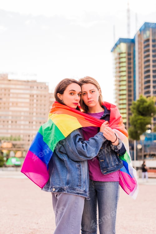Preview: Lesbian woman young multiethnic couple with a rainbow flag. Diversity concept