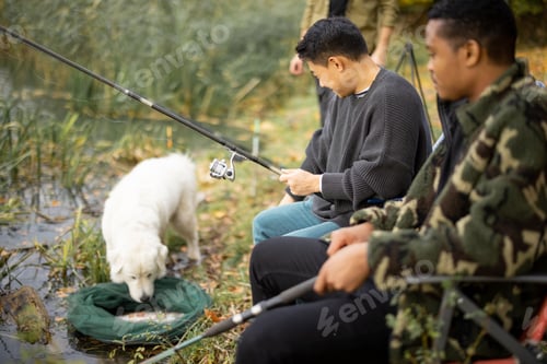 Preview: Male friends talking and fishing on lake coast