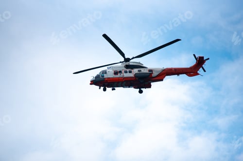 Preview: Helicopter flying in blue sky with clouds, showing rotor blades and landing gear