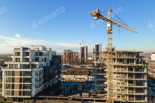 Preview: Aerial view of high tower crane and residential apartment buildings under construction.