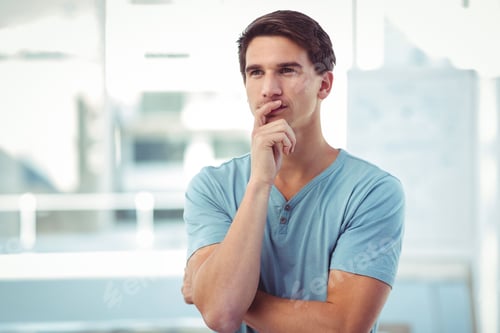 Preview: Pondering man standing with folded arms in bright modern office, with large windows