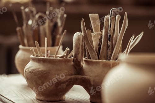 Preview: Close up of paint brushes with pottery tools in bowls on table